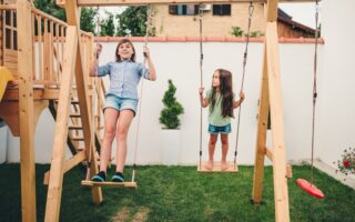 Espace de jeu pour enfants dans un jardin familial avec balançoire et petite cabane en bois.
